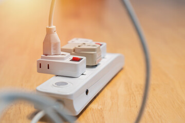 An electric plugged into maltiple electrical outlet on wooden table. Concept of electricity...