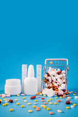 Buy and shopping medicine concept. Various capsules, tablets and medicine in the shopping cartt on a blue background. Creative idea for health care, health insurance and pharmaceutical company