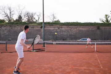 Young men playing tennis on an outdoor court