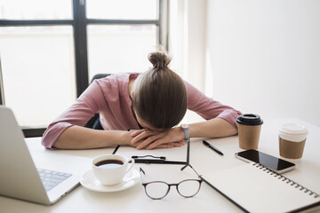 Tired and overworked business woman. Young exhausted girl sleeping on table during her work using laptop, digital tablet and smartphone. Entrepreneur, freelance worker or student in stress concept