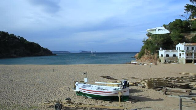 Partial view of Sa Riera beach with boat and white fishermen's houses and the sea in the background. Sa Riera cove in the village of Begur, Costa Brava (Catalonia, Spain).