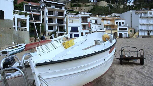 Fishing boat beached on the sand. White fishermen's houses in the background. Sa Riera cove in the village of Begur, Costa Brava (Catalonia, Spain)