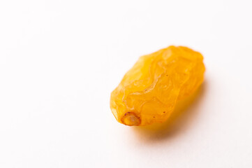macro photograph of one raisin on a white background, side view