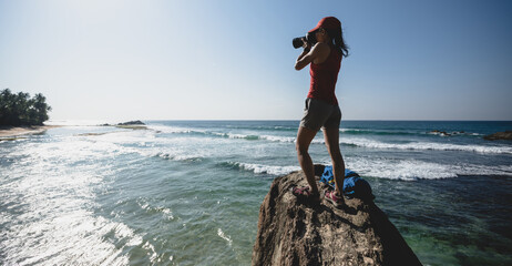 woman photographer taking photo on seaside rock cliff edge