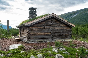 Fotobehang Оld traditional Norwegian wooden house roof covered with grass. Scandinavian style roof decoration with stone chimney and grass cover to insulate, sound insulation and protect from rain and snow. © GenоМ.