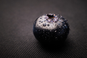 One blueberry covered with water drops on black background. Very detailed macro shoot with copy...