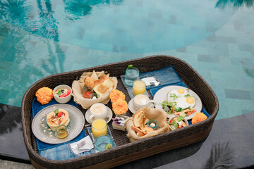 Breakfast served in tray  near swimming pool, floating breakfast in luxurious tropical resort....