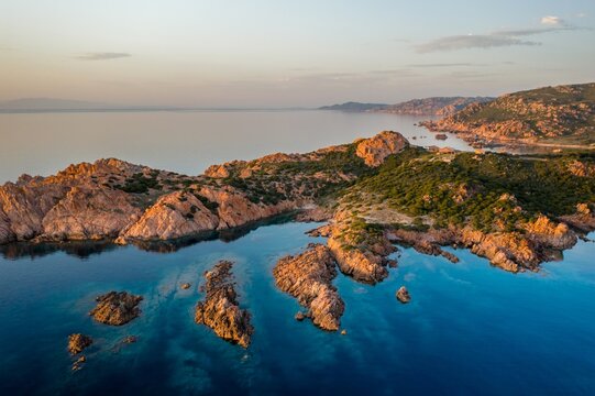 Red cliffs on turquoise water of Sardinia aerial drone view, in Italy