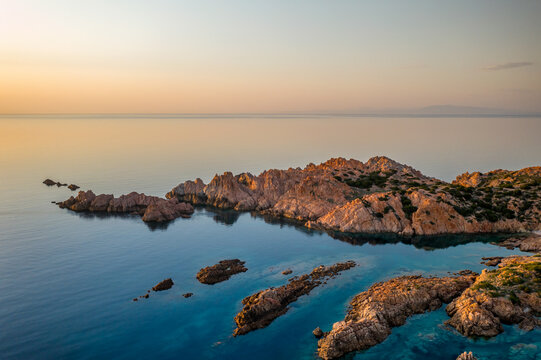 Red cliffs on turquoise water of Sardinia aerial drone view, in Italy
