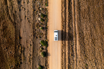 Camper van with solar panels on a dry landscape road drone top view