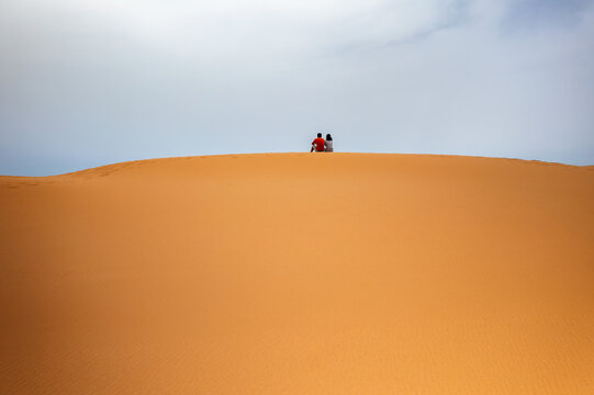 Back view of couple on top of a sand dune aerial drone view