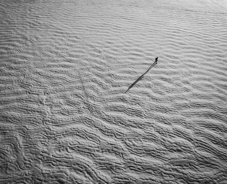 aerial view of skier on frozen snow covered lake with long shadow