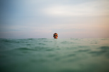 Lone swimmer in ocean exudes tranquility at dusk