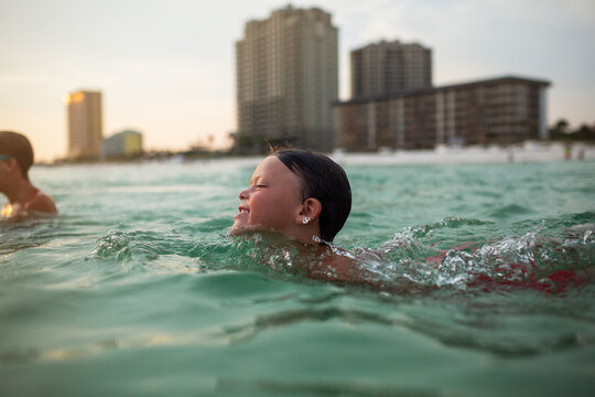 Joyful child swimming at sunset by the beach skyline