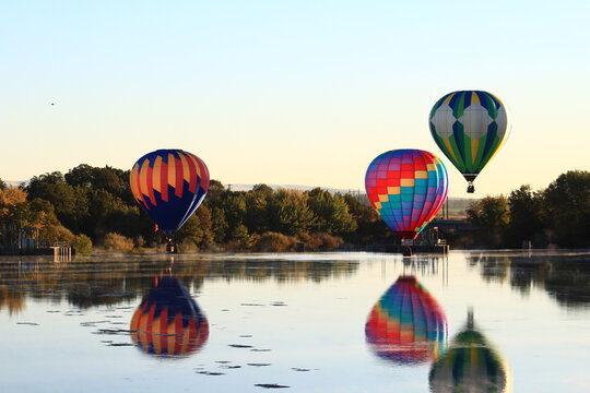 Dawn ascent of vibrant balloons over water