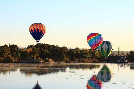 Dawn ascent of vibrant balloons over water