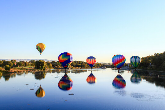 Dawn ascent of vibrant balloons over water
