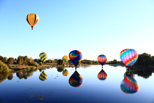 Dawn ascent of vibrant balloons over water
