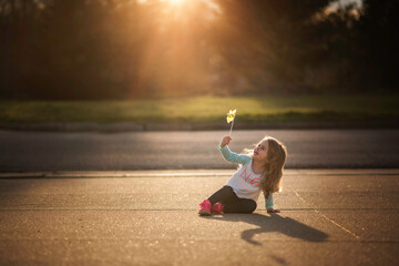 Beautiful happy little girl playing with pinwheel outdoors in sunshine