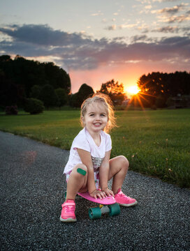 Beautiful happy girl riding skateboard with bandaid on knee