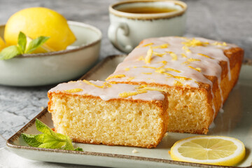 Glazed lemon pound cake loaf with lemon zest closeup on the plate on the table. Horizontal