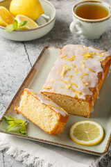 Lemon loaf cake, classic recipe, decorated with sugar icing closeup on the plate on the table. Vertical