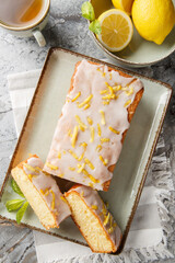 Lemon Drizzle Cake is a classic British cake known for its moist texture and vibrant lemon flavour closeup on the plate on the table. Vertical top view from above
