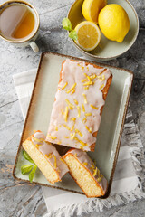 Lemon loaf cake, classic recipe, decorated with sugar icing closeup on the plate on the table. Vertical top view from above