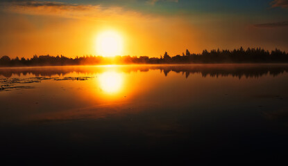 The first minutes of sunrise over the river, the sun disc appeared from behind the forest horizon,...