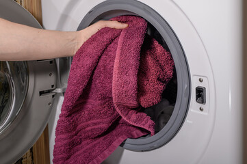 Robić pranie, wkładać ubrania i ręczniki do bębna pralki - obrazy, fototapety, plakaty