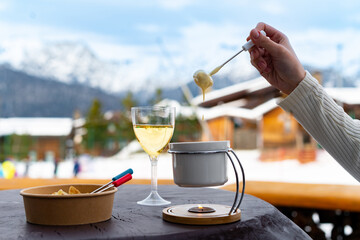 Savor alpine indulgence with fine wine and a fondue set, against the backdrop of a snowy mountain...