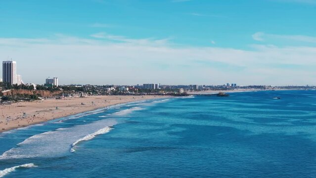 Slow cinematic shot flying over the pacific ocean and Santa Monica Beach, CA