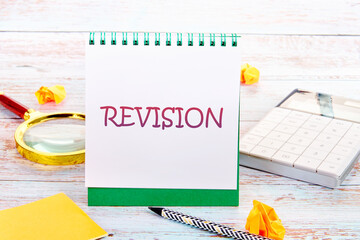 Business concept. REVISION word in a notebook next to a calculator, magnifying glass, pencil and...