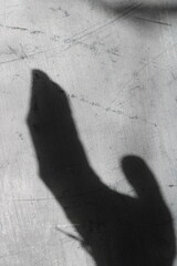 the shadow of a hand on a gray background - obrazy, fototapety, plakaty