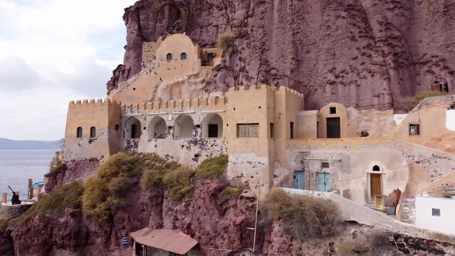Santorini Greece, Castle Resort Building on a Cliff Face, White Buildings Overlooking Mediterranean Sea. Cruise Ship Port at Base of Gondola Cable Car.