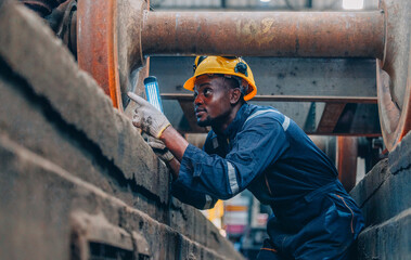 Rail technician inspects train wheels with flashlight for faults and wear during routine checks.