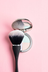 Top view of compact powder with different correcting colours and black brush on pink background, close up - 793679918