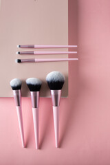 Top view of professional make up brush set on beige podium at pink background - obrazy, fototapety, plakaty