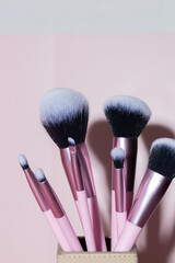 Close up of different make up brushes at pink background, professional cometic tools - obrazy, fototapety, plakaty