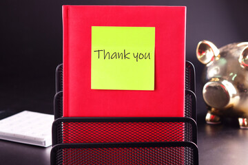 Text Thank You on a yellow sticker glued to a red notebook - obrazy, fototapety, plakaty