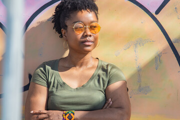 young afro woman with arms crossed on graffiti wall