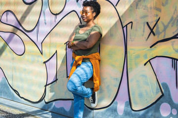 portrait of woman with arms crossed on graffiti wall