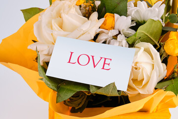 LOVE The concept of relationships and love. text love on a business card in a bouquet of flowers - obrazy, fototapety, plakaty