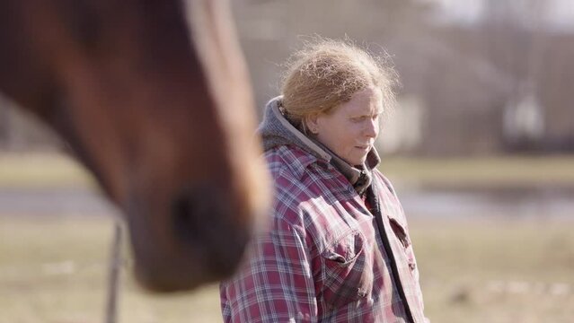 Woman near horse with eyes closed speaks words of affirmation, rack focus