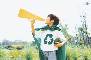 Young superhero boy with recycle symbol and cape make announcement with speaker on environmental...