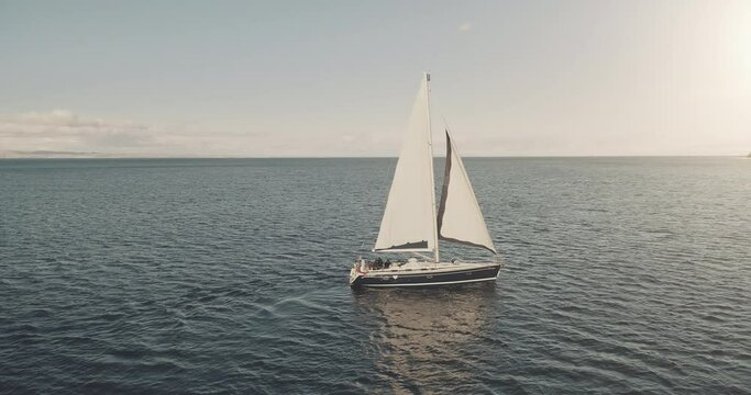 Sun at ocean bay with luxury yacht aerial. Nobody nature seascape at sunlight summer cruise. Sail boat at open sea. White sailing ship on water at cinematic drone shot. Travel and tourism concept