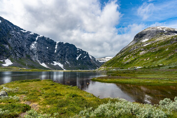 Norwegian mountains. Panorama. Amazing breathtaking landscape. Northern mountains with glaciers. Glacier lake and reflections on turquoise water.  Stanning view of Scandinavia. 
