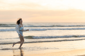 A woman is running on the beach with the sun setting in the background