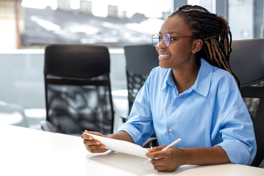 Smiling woman sitting at desk in office with paper documents