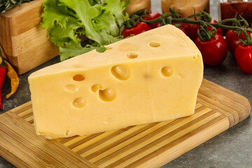 Swiss Maasdam cheese triangle over board